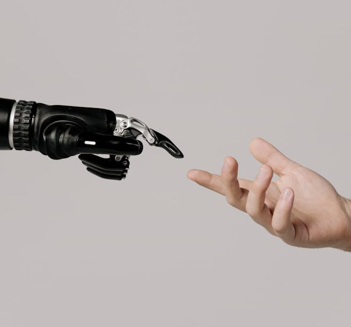 A human hand reaching to touch a bionic prosthetic hand on a white background.
